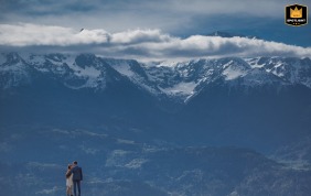 Bride and groom standing in front of dramatic mountain scenery in Saint Hilaire du Touvet, France.